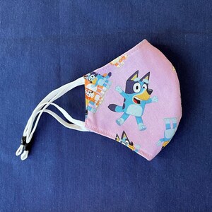 Bluey Face Mask for Child or Toddler: 2-Layer Cotton. Colors available are Blue and Pink. Also baby bib and tote bag. Mask302BlueyDoC2-7Pk