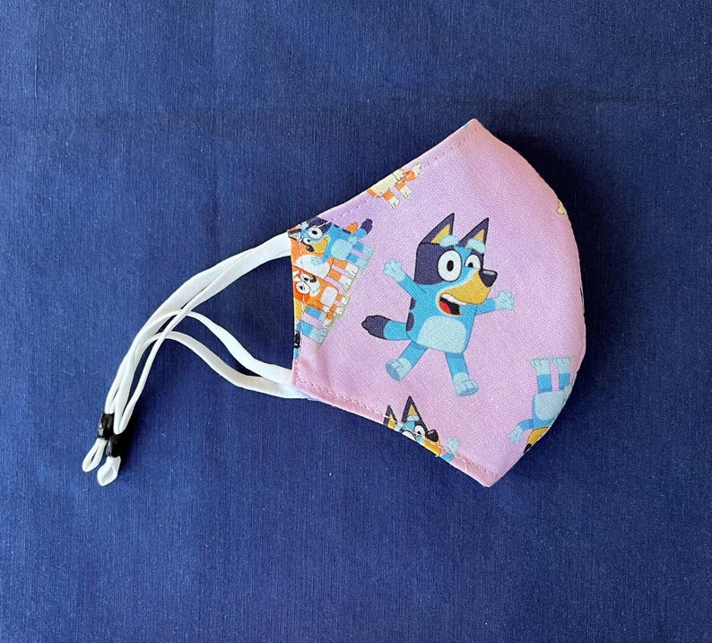 Bluey Face Mask for Child or Toddler: 2-Layer Cotton. Colors available are Blue and Pink. Also baby bib and tote bag. Mask302BlueyDoC2-7Pk
