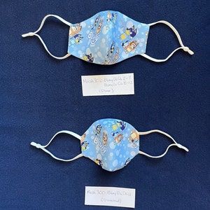 May include: Two blue and white face masks with a cartoon dog pattern. The masks are labeled "Mask 302 - Bluey Do Ch 2-7 Bluey Do Ch 8-12 (Dame)" and "Mask 300 - Bluey Do Child (Dickoned)".