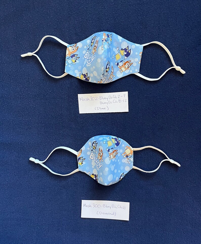 May include: Two blue and white face masks with a cartoon dog pattern. The masks are labeled "Mask 302 - Bluey Do Ch 2-7 Bluey Do Ch 8-12 (Dame)" and "Mask 300 - Bluey Do Child (Dickoned)".