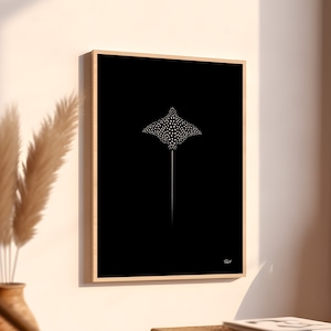 May include: A black and white minimalist print of a spotted ray, framed in a thin wooden frame. The print is hanging on a white wall.