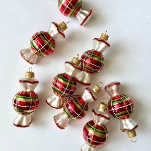 May include: Set of seven red, green, and gold candy cane Christmas ornaments. The ornaments are shaped like candy canes and have a white, frosted finish.