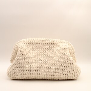 Pu&ograve; includere: Una borsa tote in crochet color crema con una superficie testurizzata.