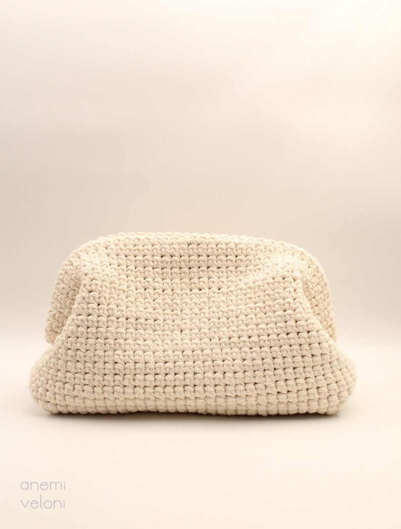 Pu&ograve; includere: Una borsa tote in crochet color crema con una superficie testurizzata.
