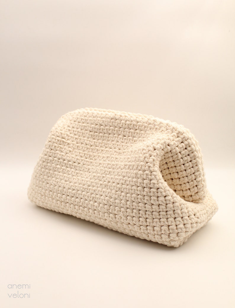 Pu&ograve; includere: Una borsa a uncinetto color crema con una forma unica e curva. La borsa &egrave; realizzata con un filato spesso e testurizzato e ha un aspetto morbido e naturale.