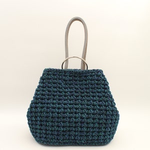 May include: A dark blue and green crocheted tote bag with a silver ring handle and light gray leather straps.