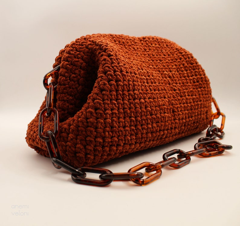 May include: A brown crocheted handbag with a thick, brown chain strap.