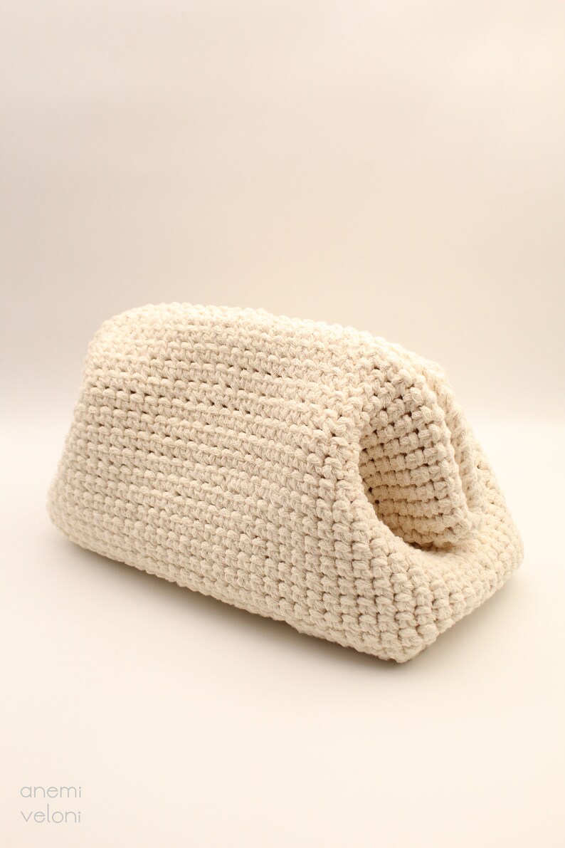 Pu&ograve; includere: Una borsa in crochet color crema con un design unico a apertura superiore. La borsa &egrave; realizzata in filato spesso e testurizzato e ha un aspetto morbido e naturale.