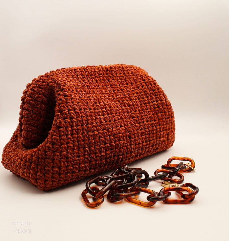 May include: A rust-coloured crocheted bag with a brown plastic chain strap.
