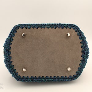 May include: A blue and green crocheted handbag with a brown suede lining and silver metal accents.