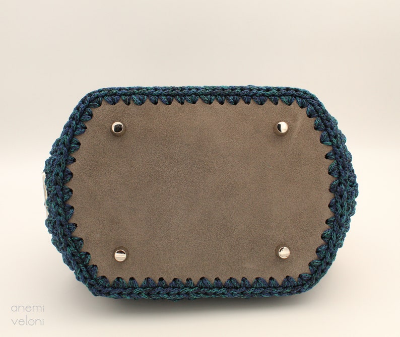 May include: A blue and green crocheted handbag with a brown suede lining and silver metal accents.
