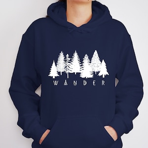 May include: Navy blue hoodie with a white graphic of a forest silhouette and the word "WANDER" underneath.