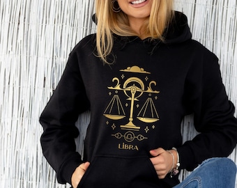 May include: Black hoodie with a gold Libra zodiac sign and the word "LIBRA" printed on the front.