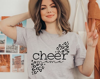 May include: A gray t-shirt with a black graphic that says "cheer mama" with a leopard print design.