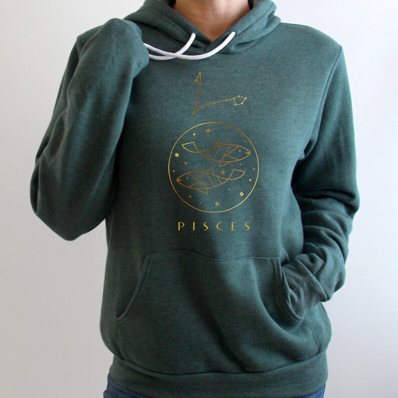 May include: A dark green hoodie with a gold outline of the Pisces zodiac sign and the word "Pisces" printed on the front.