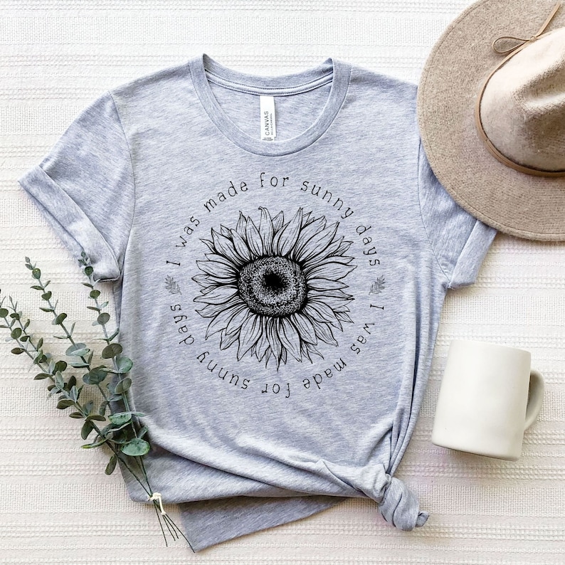 May include: A gray t-shirt with a black sunflower graphic and the text "I was made for sunny days I was made for sunny days".