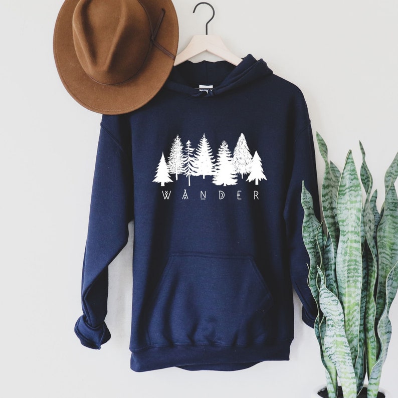 May include: Navy blue hooded sweatshirt with a white graphic of a forest silhouette and the word "WANDER" underneath.