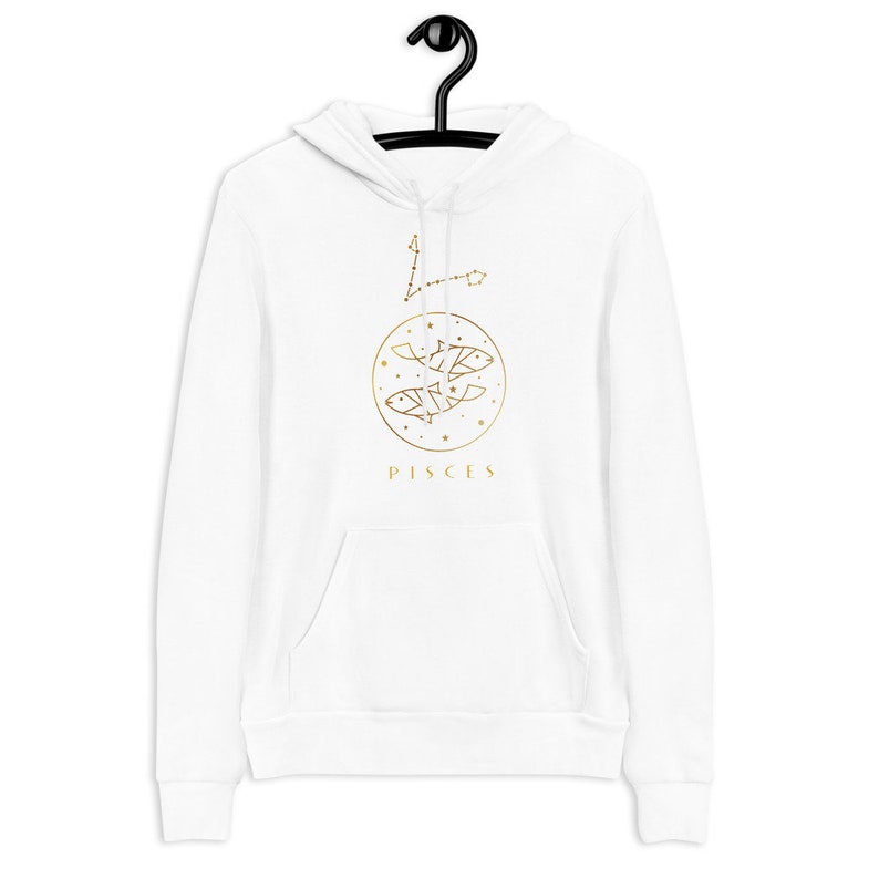 May include: White hoodie with a gold Pisces zodiac sign and constellation design. The design features two fish and stars in a circle with the word "Pisces" below.