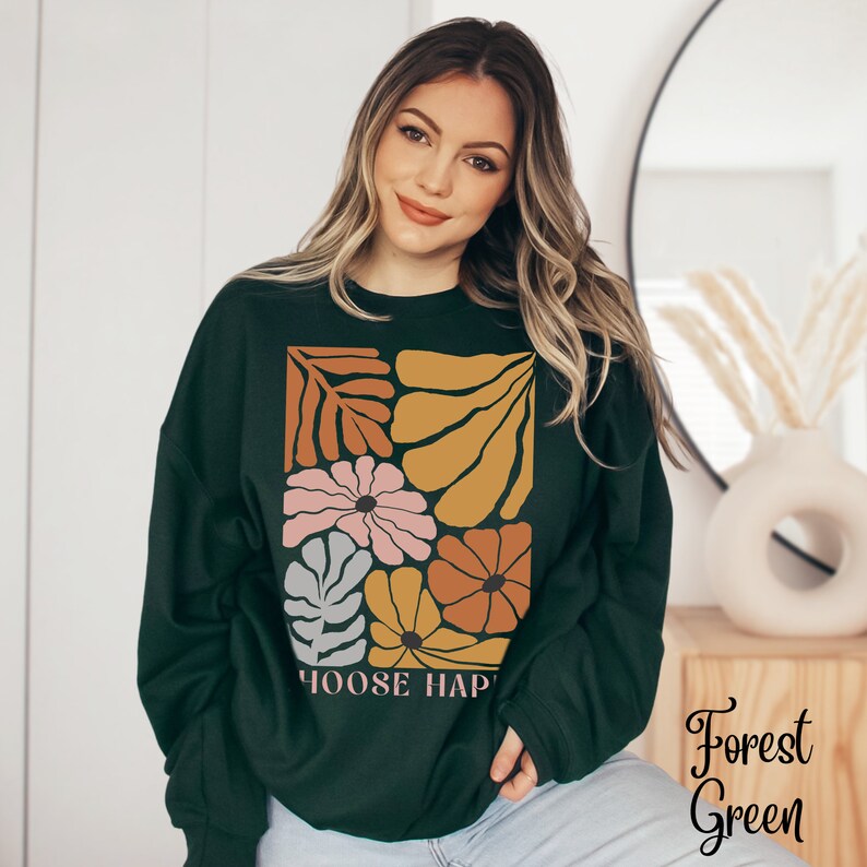 May include: A dark green sweatshirt with a floral design in shades of orange, yellow, pink, and gray. The text "Choose Happy" is printed on the bottom of the sweatshirt.