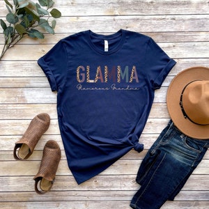 May include: A navy blue t-shirt with the text "GLAMMA Glamorous Grandma" in colorful letters with a leopard print design.