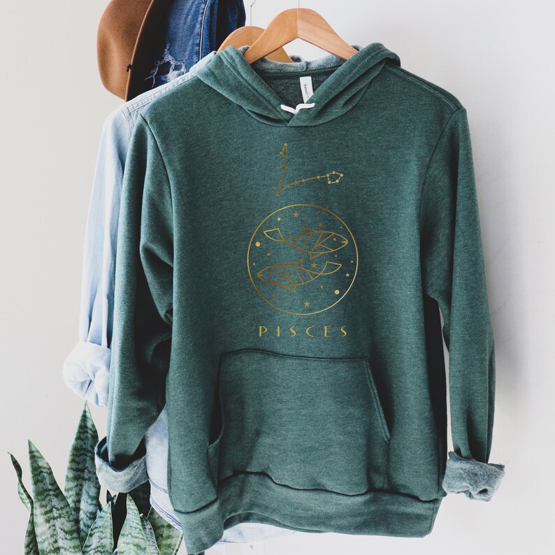 May include: A dark green hoodie with a gold graphic of the Pisces zodiac sign and the word "Pisces" printed below.