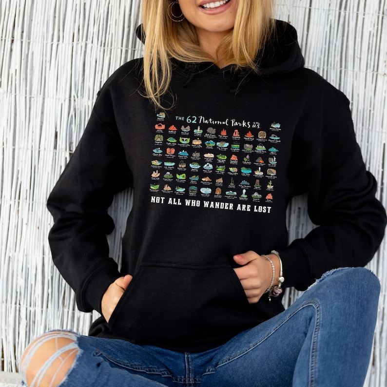 May include: A black hoodie with a graphic of the 62 National Parks in the United States. The graphic is a colorful illustration of each park's unique features. The text "The 62 National Parks" and "Not all who wander are lost" is printed on the hoodie.