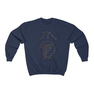 Puede incluir: Sudadera azul marino con un contorno dorado de la constelaci&oacute;n de Acuario y la palabra "Aquarius" impresa debajo.