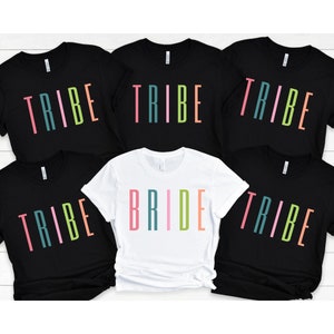 以下が含まれることがあります： カラフルな文字で「TRIBE」と書かれた黒いTシャツが5枚と、カラフルな文字で「BRIDE」と書かれた白いTシャツが1枚