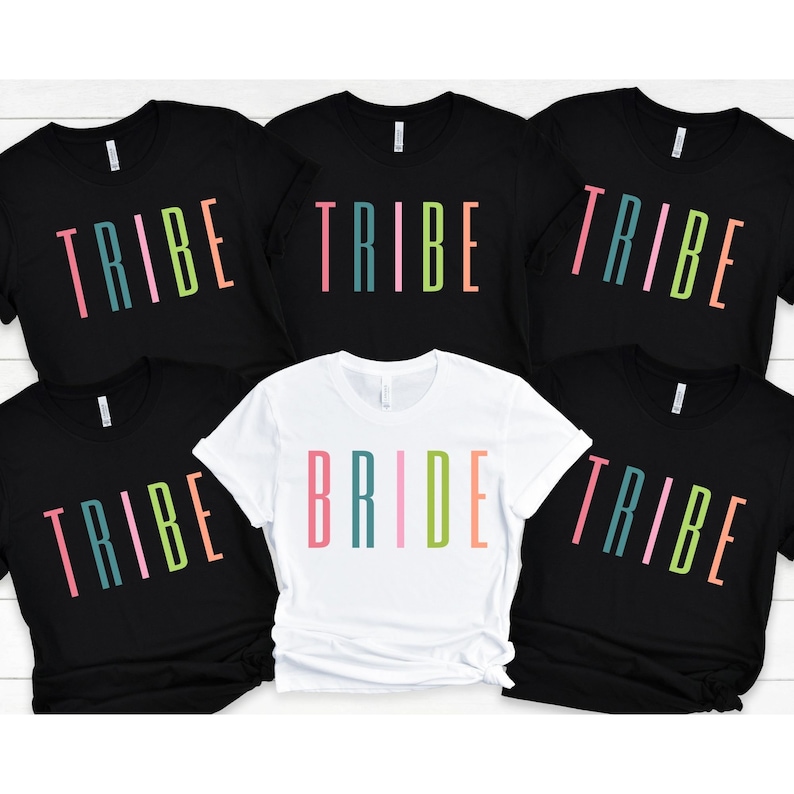以下が含まれることがあります： カラフルな文字で「TRIBE」と書かれた黒いTシャツが5枚と、カラフルな文字で「BRIDE」と書かれた白いTシャツが1枚