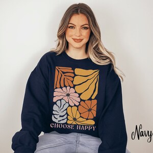 May include: Navy blue sweatshirt with a colorful floral design and the text "CHOOSE HAPPY" printed on the front.