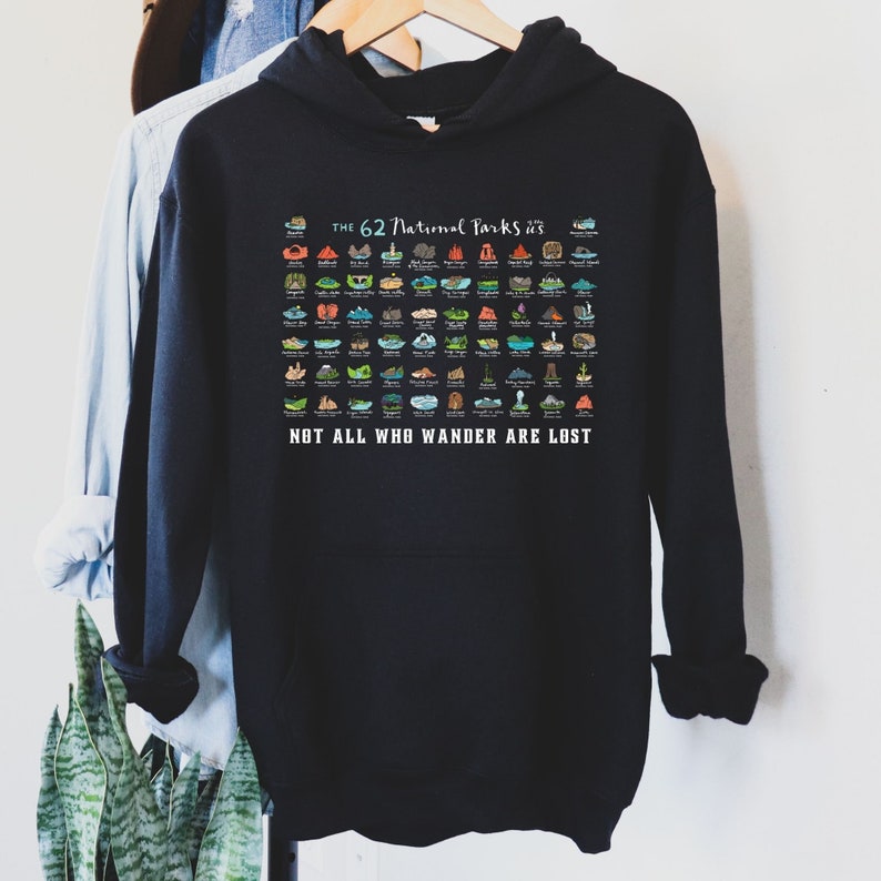 May include: Black hooded sweatshirt with a graphic of the 62 National Parks in the United States. The graphic is a colorful illustration of each park's iconic landmark. The text "THE 62 National Parks" is at the top of the graphic, and the text "NOT ALL WHO WANDER ARE LOST" is at the bottom.