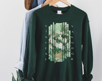 May include: A dark green sweatshirt with a white graphic print of a vase of white flowers. The graphic is broken up into vertical stripes with the text "Vincent Van Gogh" printed vertically on either side of the image.