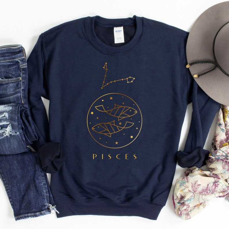 May include: Navy blue sweatshirt with a gold outline of the Pisces zodiac constellation and the word "Pisces" in gold lettering.