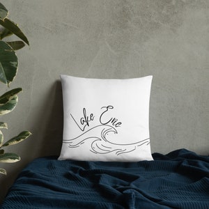 May include: White pillow with black text and a wave design. The text reads "Lake Evie".