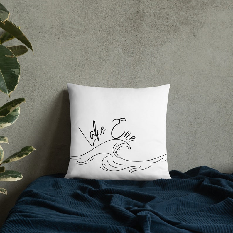May include: White pillow with black text and a wave design. The text reads "Lake Evie".
