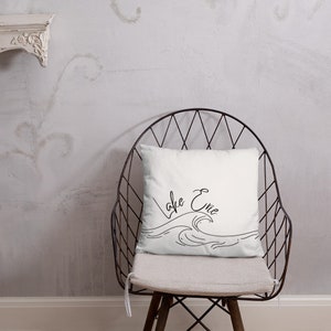 May include: White throw pillow with black cursive text that reads "Lake Erie" and a simple line drawing of waves.