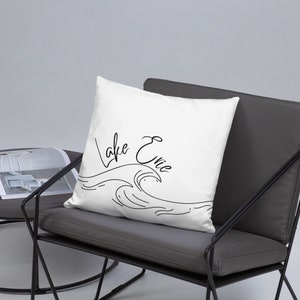 May include: White throw pillow with black cursive text that reads "Lake Erie" and a black line drawing of a wave.