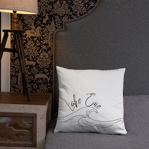 May include: White pillow with black text that says "Lake Erie" and a stylized wave design.