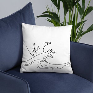 May include: White throw pillow with black text that reads "Lake Erie" and a black line drawing of a wave.