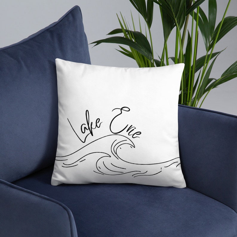 May include: White throw pillow with black text that reads "Lake Erie" and a black line drawing of a wave.