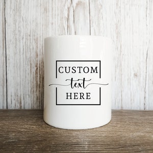 May include: White ceramic money box with a black square border and the text "CUSTOM text HERE" inside.