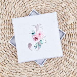 May include: A white gift box with a floral design featuring a pink and white watercolour letter J.