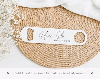 May include: A white flat bottle opener featuring the black printed text Uncle Stu and GODFATHER. The tool has a rectangular shape with rounded ends, a circular hole on one side, and a notched opening on the other for removing bottle caps.