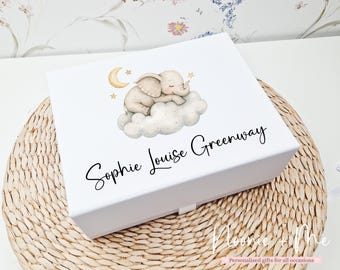 May include: A white keepsake box with a sleeping elephant illustration on the lid. The box features the name "Sophie Louise Greenway" in black script. The box is on a woven mat.