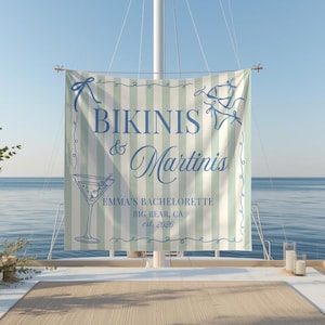 May include: A banner with the words "Bikinis & Martinis" in blue script, with a martini glass illustration. The banner has a light green and white striped background and includes the text "Emma's Bachelorette, Big Bear, CA, est. 2026".