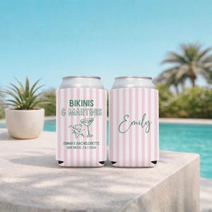 Może przedstawiać: Dwa kubki na puszki w r&oacute;żowo-białe paski. Jeden ma napis "BIKINIS & MARTINIS" z grafiką kieliszka do martini i "EMMA'S BACHELORETTE SAN DIEGO, CA I 2026". Drugi ma imię "Emily" w zielonym skrypcie.
