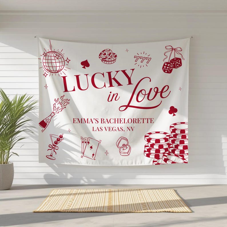 May include: White fabric banner with red illustrations of casino-themed elements, including dice, playing cards, and poker chips. The banner reads "LUCKY in Love" and "EMMA'S BACHELORETTE LAS VEGAS, NV".