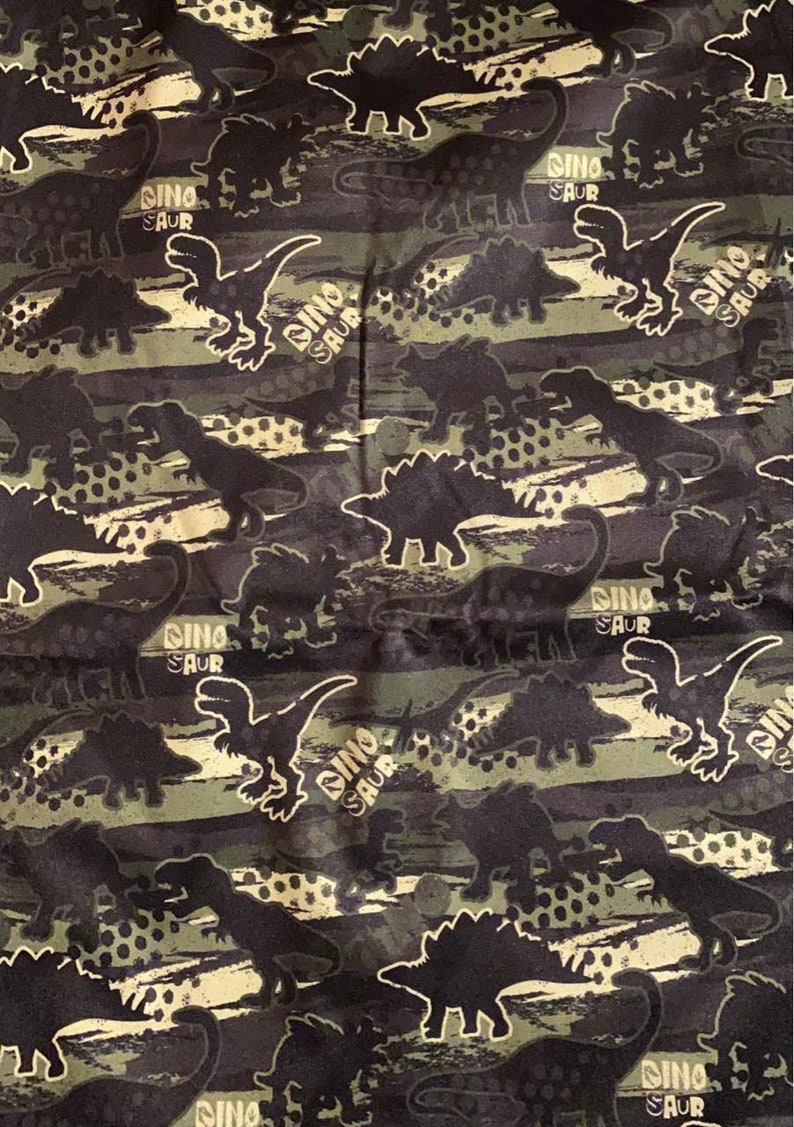 May include: A black and green fabric with a repeating pattern of dinosaurs. The dinosaurs are in a variety of poses, including walking, running, and roaring. The fabric has a camouflage pattern with brown, green, and black colors.