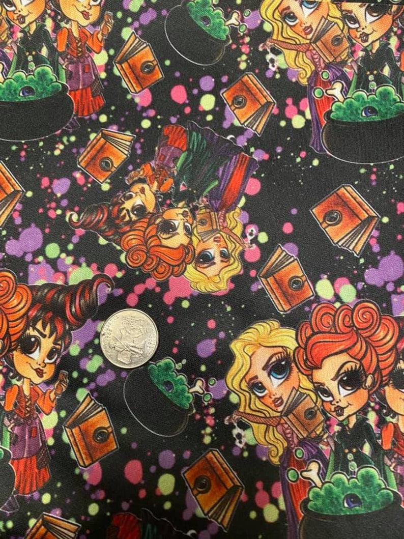 May include: A black fabric with a repeating pattern of witches, cauldrons, and books. The witches are wearing purple and green dresses and have large eyes. The cauldrons are green and have steam coming out of them. The books are brown and have a gold design on them. The background is black with colorful paint splatters.