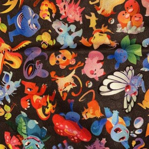 May include: A black fabric with a colorful pattern of various cartoon characters. The characters are all different colors and shapes, and they are arranged in a random pattern. The fabric is perfect for a variety of projects, such as making clothes, bags, or home decor.